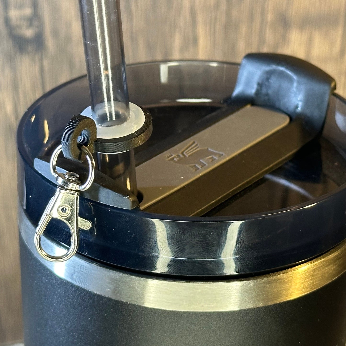 a metal clasp is attached to a tumbler straw using a plastic ring and grommet