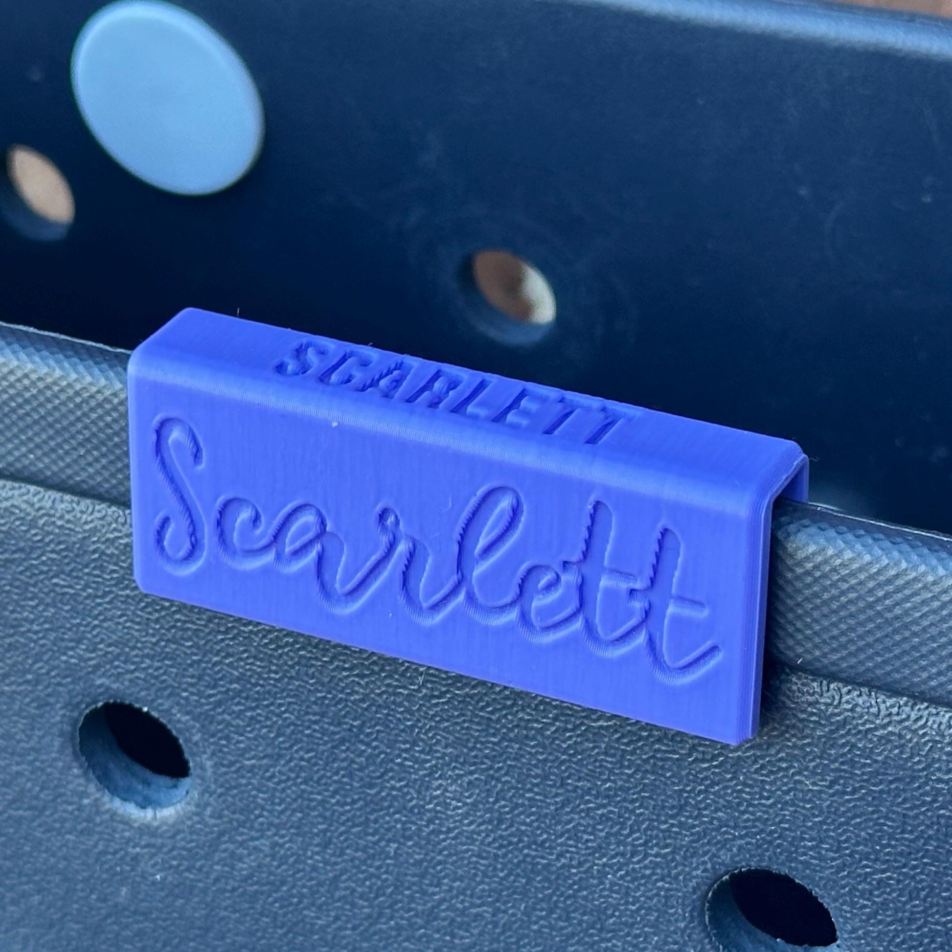 a blue plastic nameplateon a blue bogg bag edge